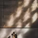 Asian couple kissing in a light-filled room with sunlight through the window against the cobblestone wall