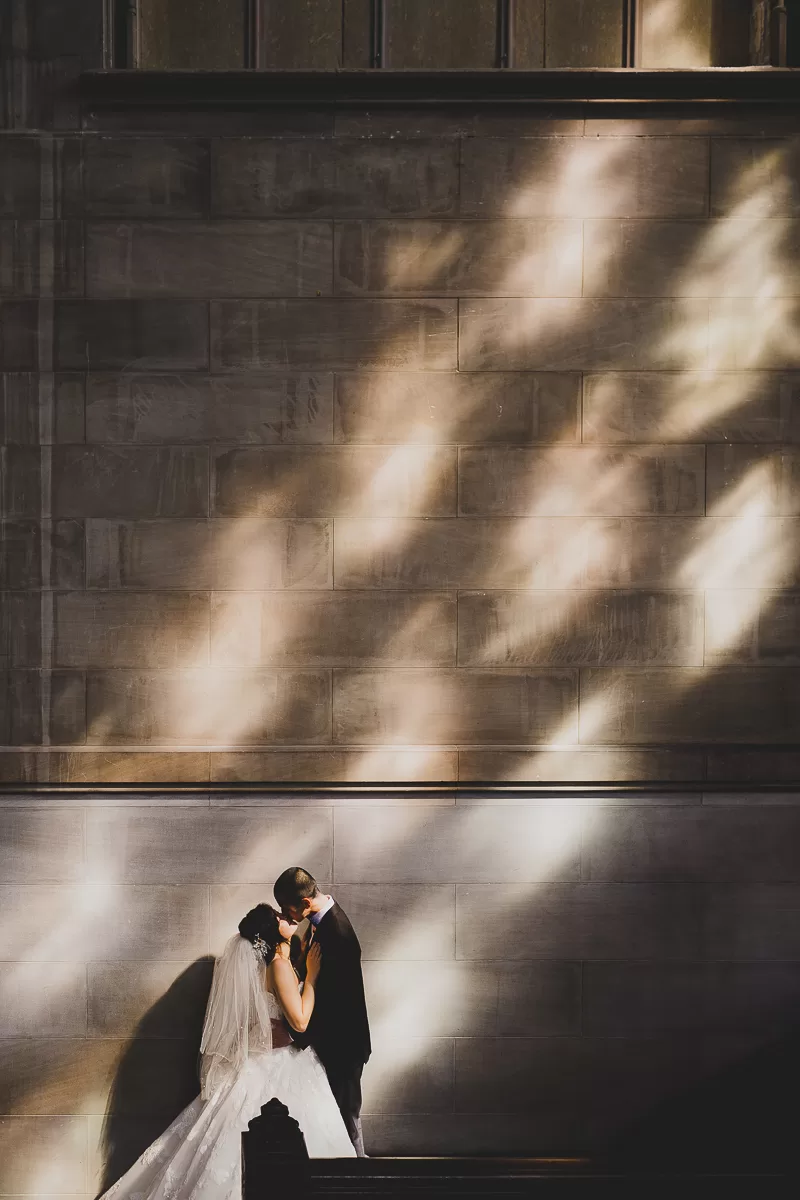 Asian couple kissing in a light-filled room with sunlight through the window against the cobblestone wall