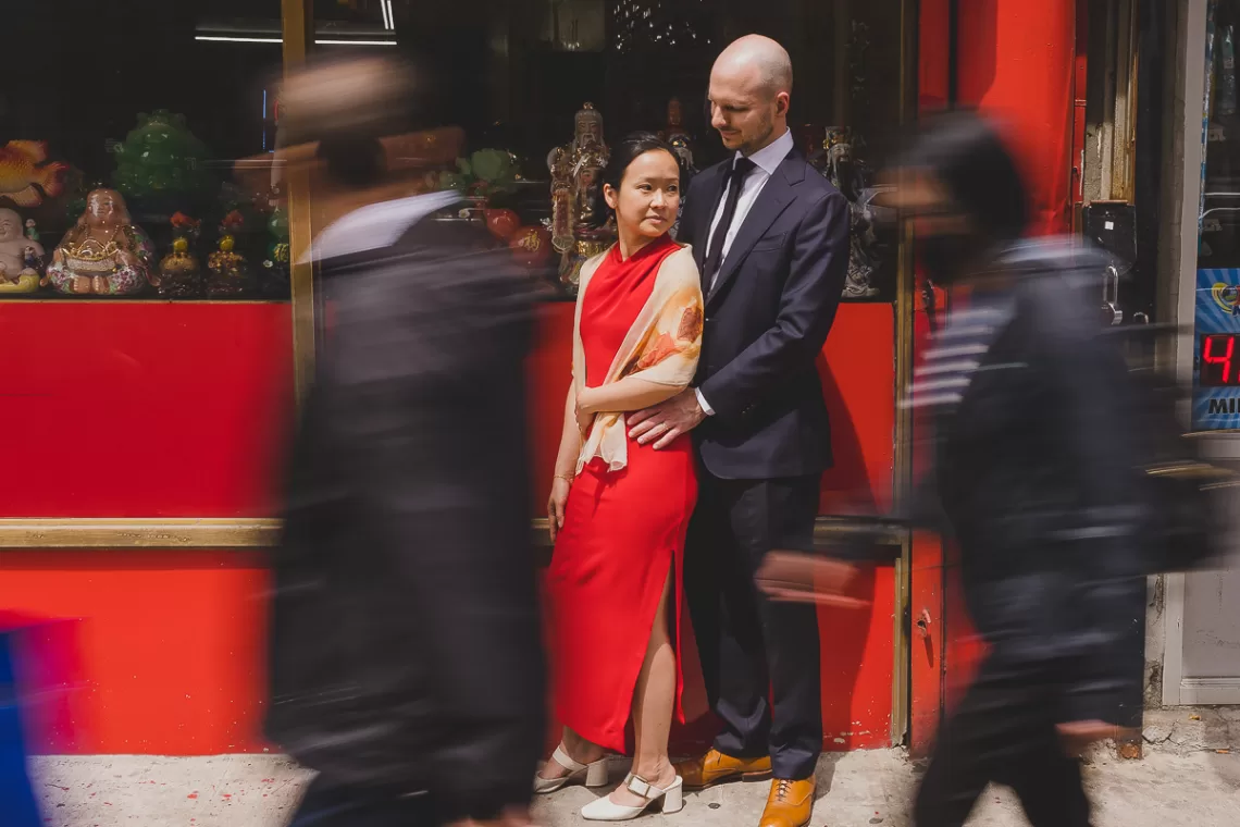 Couple holding to each other in Chinatown while blurred people are walking past them