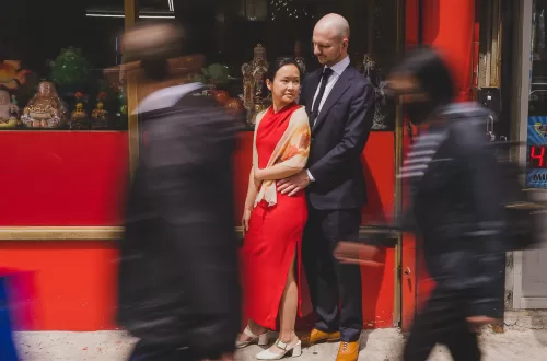 Couple holding to each other in Chinatown while blurred people are walking past them