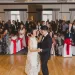 Asian Couple dancing together on the dance floor with guests behind them cheering them on.