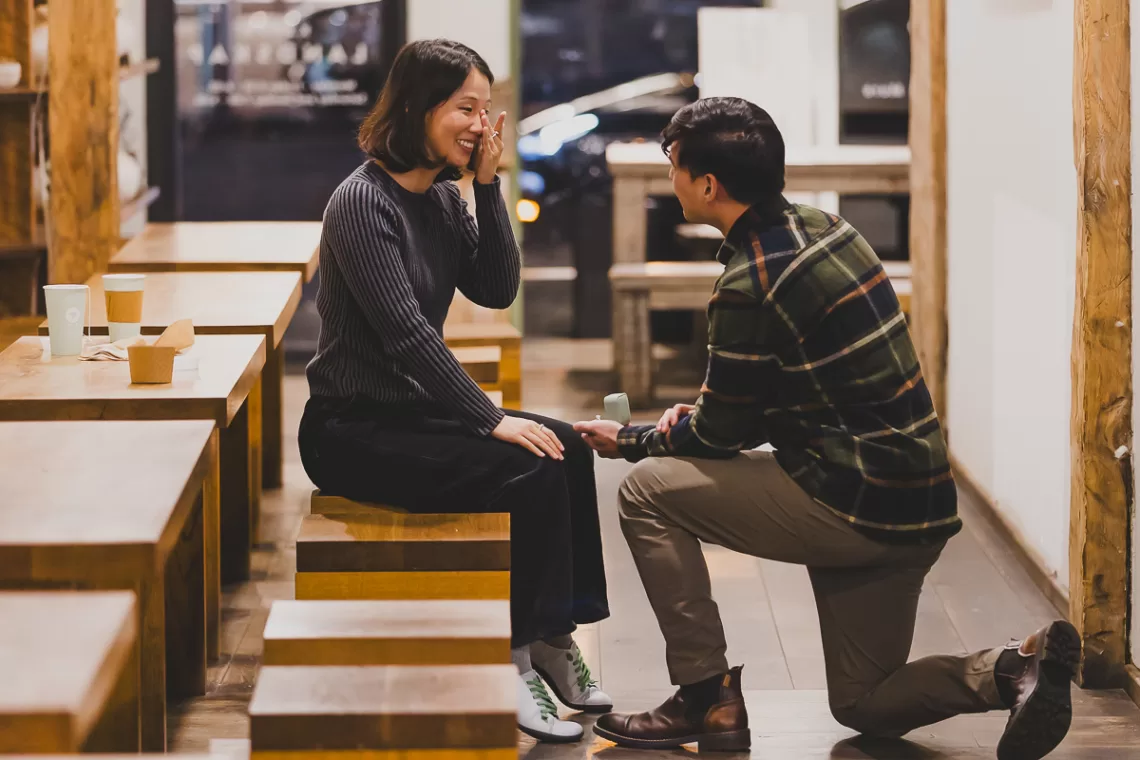 asian couple in an empty coffee shop being proposed to