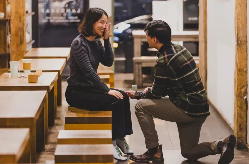 asian couple in an empty coffee shop being proposed to