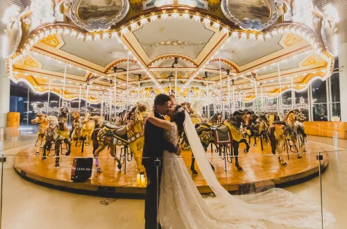 Asian couple in front of horse carousel kissing